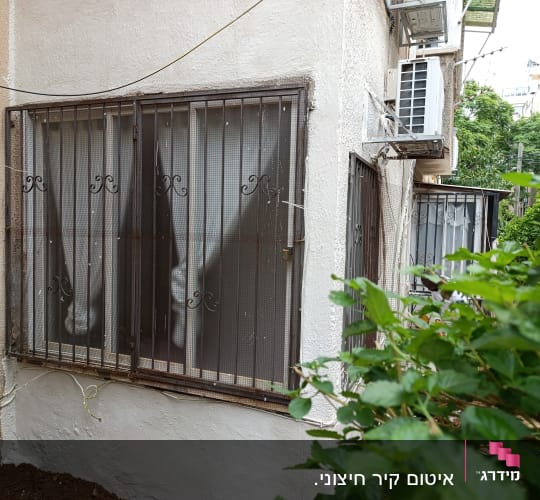 חלון עם סורגים וחוטים חשמליים מחוברים לקיר